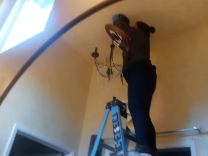 Electrician installing a chandelier in a Mount Olive residence